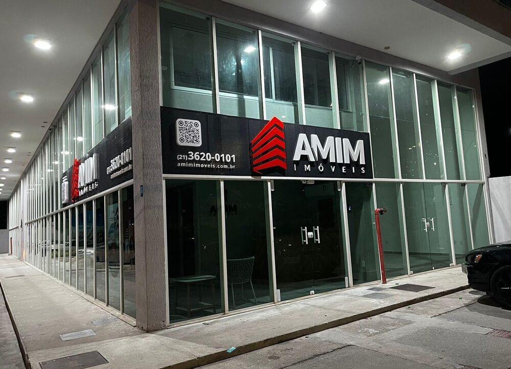 Fachada em ACM preto com logo iluminado: Amim Imóveis
